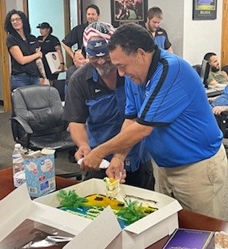 Jose Gomez cutting cake at his retirement party